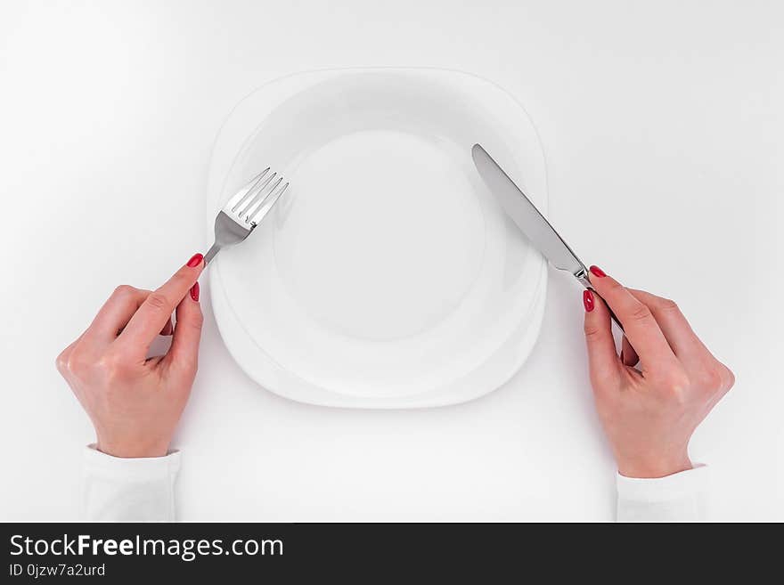 Hands with cutlery over empty plate. A place to place your image.