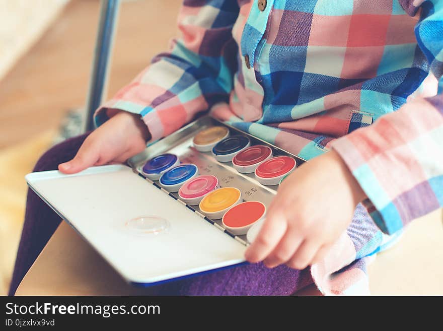 Little cute girl holds a set of color paints for painting face.