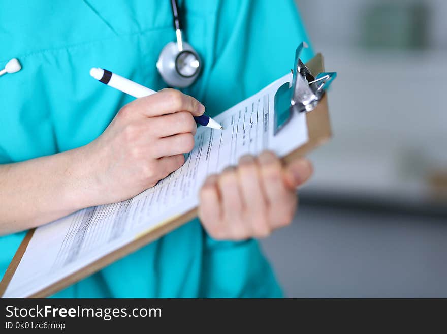 Female doctor filling up medical form on clipboard closeup. Physician finish up examining his patient in hospital an