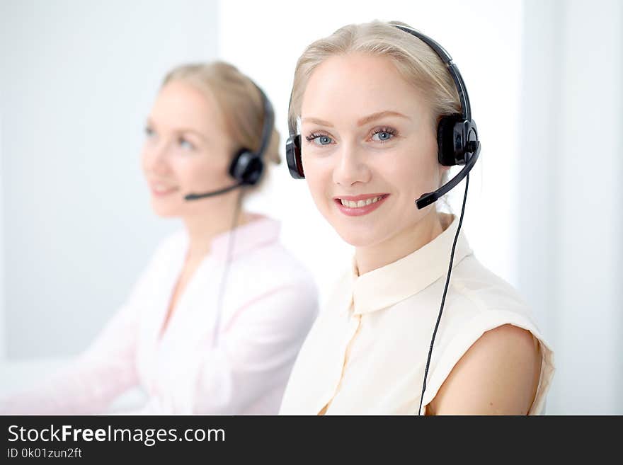 Image of bright call center. Focus on young beautiful woman in a headset