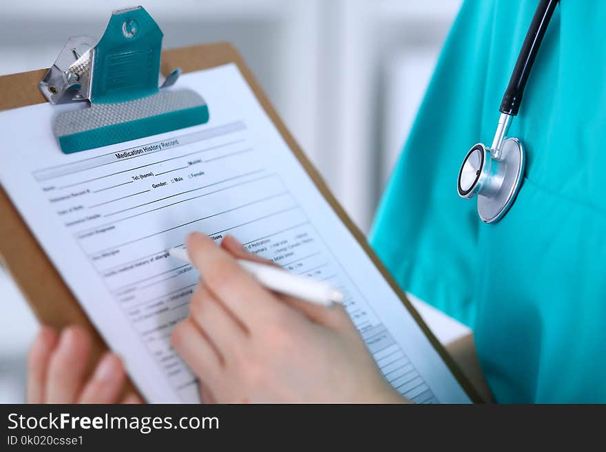 Female doctor filling up medical form on clipboard closeup. Physician finish up examining his patient in hospital an