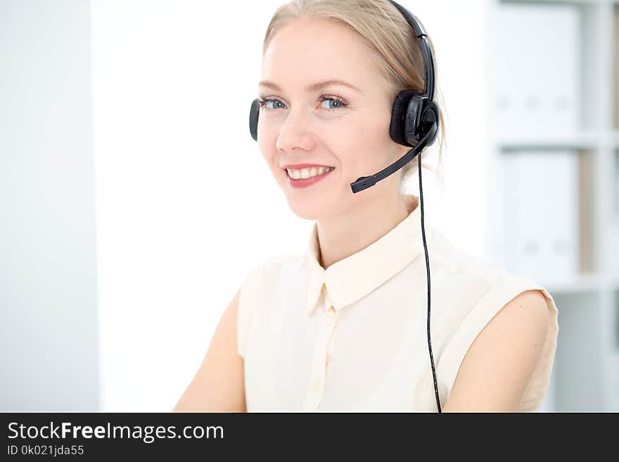 Image of bright call center. Focus on young blonde woman in a headset. Image of bright call center. Focus on young blonde woman in a headset.