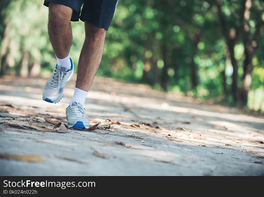 Close up foot of young runner man running along road in the park.