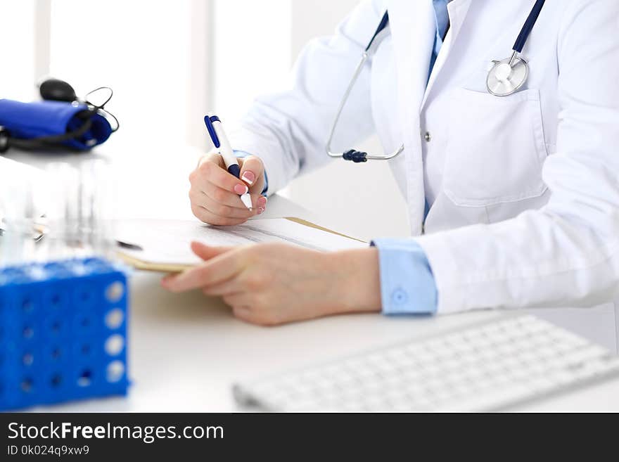 Female doctor filling up medical form on clipboard closeup. Physician finishing up examining his patient in hospital an