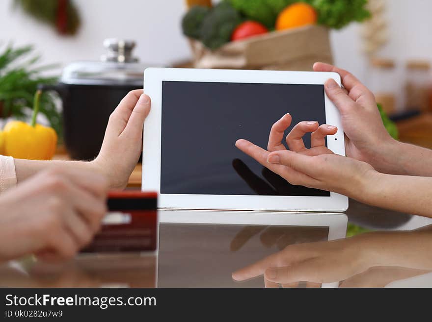 Closeup of human hands cooking in kitchen. Women discuss a menu using tablet computer. Copy space area at touch pad