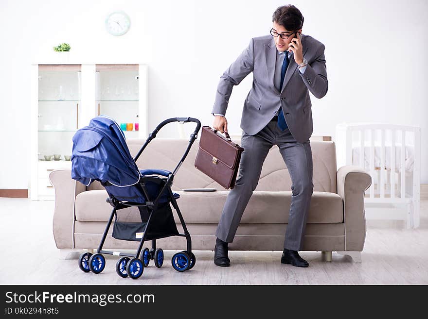 The businessman looking after newborn baby at home and teleworking