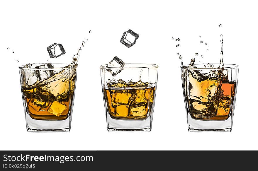 Three glasses of splashing whiskey with ice on white