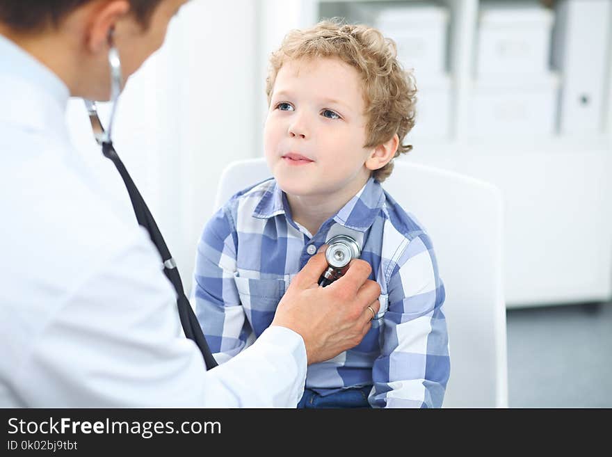 Doctor and child patient. Physician examines little boy by stethoscope. Medicine and children`s therapy concept.