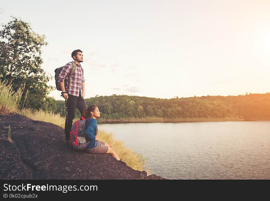 Couple having rest on the top of mountain below lake view during