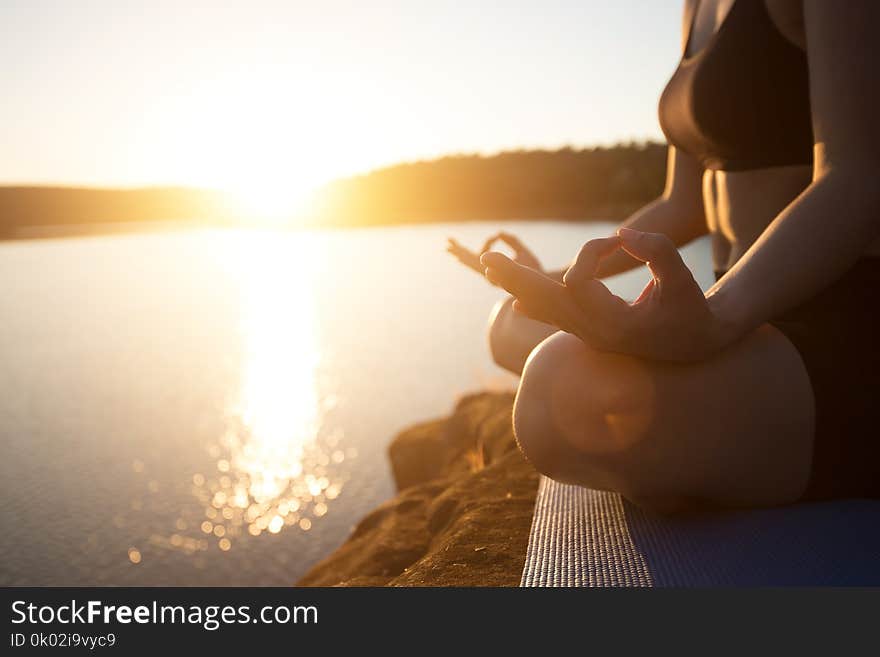 Young healthy woman is practicing yoga at mountain lake during s