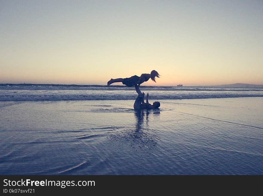 Landscape Photography of Man Lifting Woman by His Foot on Seashore