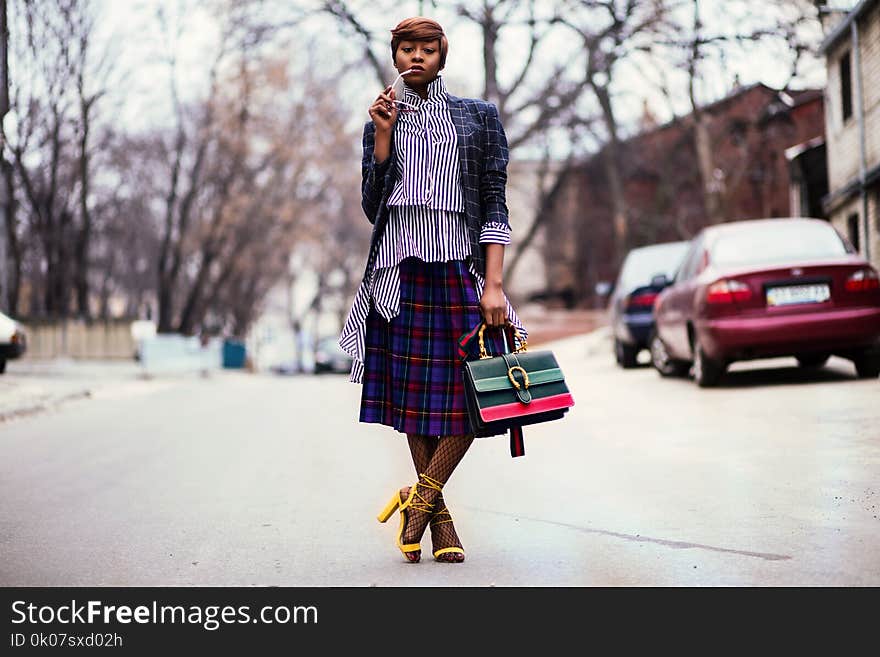 Woman Holding Handbag Beside Red Car on Road