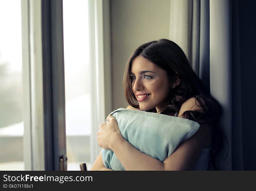 Woman Hugging White Pillow Beside Glass Door