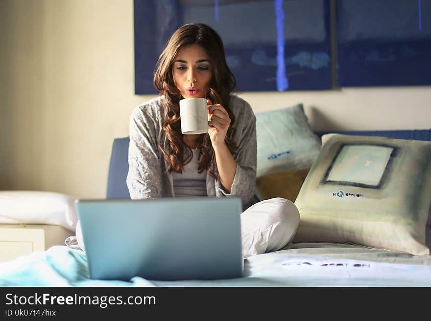 Woman in Grey Jacket Sits on Bed Uses Grey Laptop