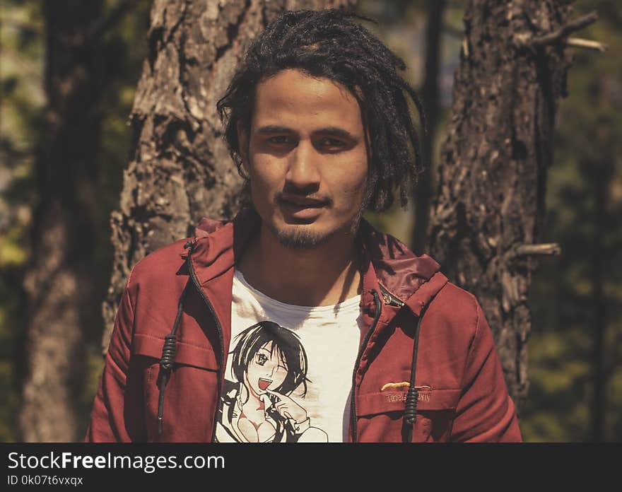 Man in Red Jacket Stands Near Trees at Daytime