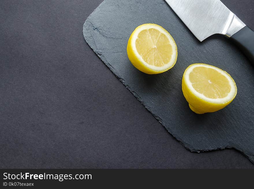 Sliced Lemon Beside Knife on Top of Black Surface