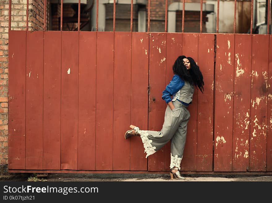 Woman Wearing Grey Jumpsuit Standing Beside Brown Metal Gate