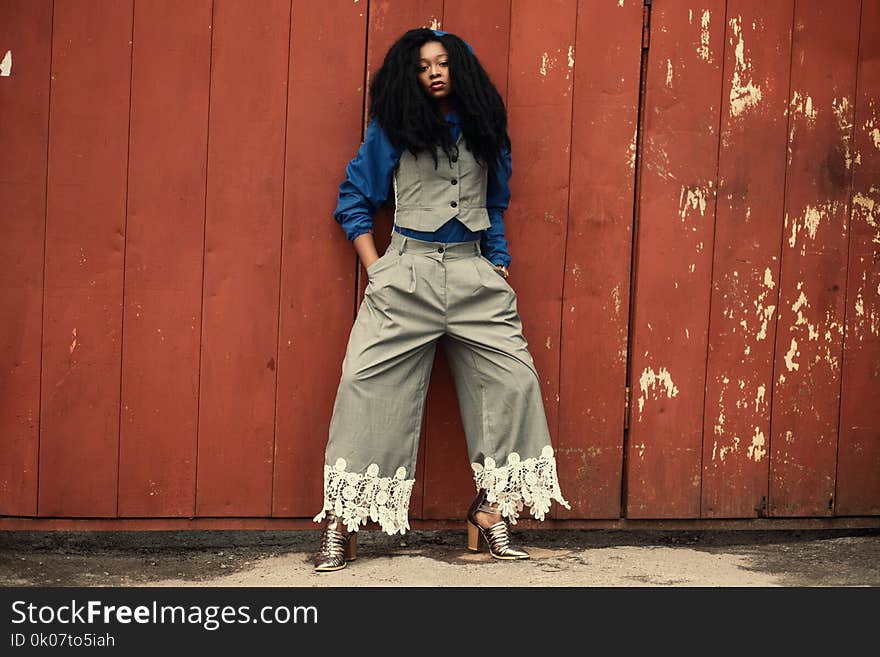 Woman in Blue and Grey Suit Leaning on Brown Wooden Wall