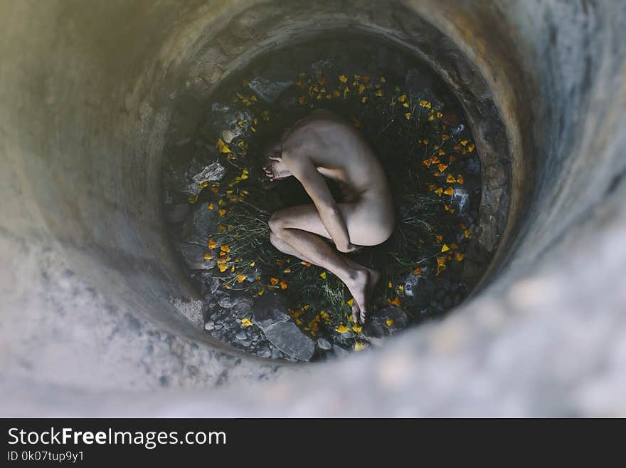 Nude Person Inside Well Laying on Flowers