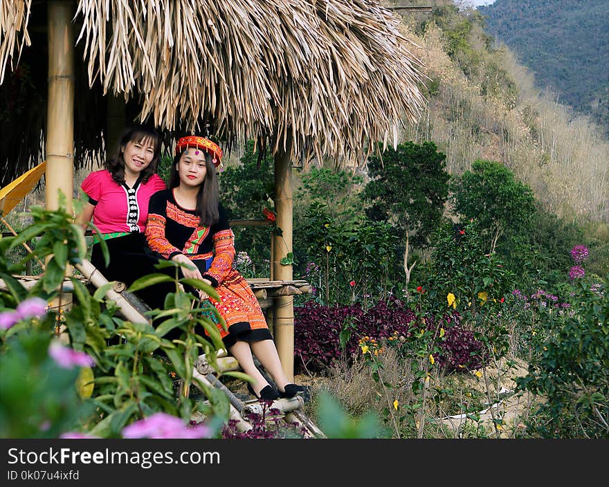 Person in Traditional Dress Sitting on Hut