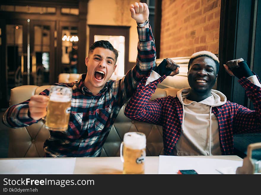 Cheerful Male Friends Having Fun At The Beer Pub Celebrating Victory Of Their Favorite Team Watching Game On TV And Shouting