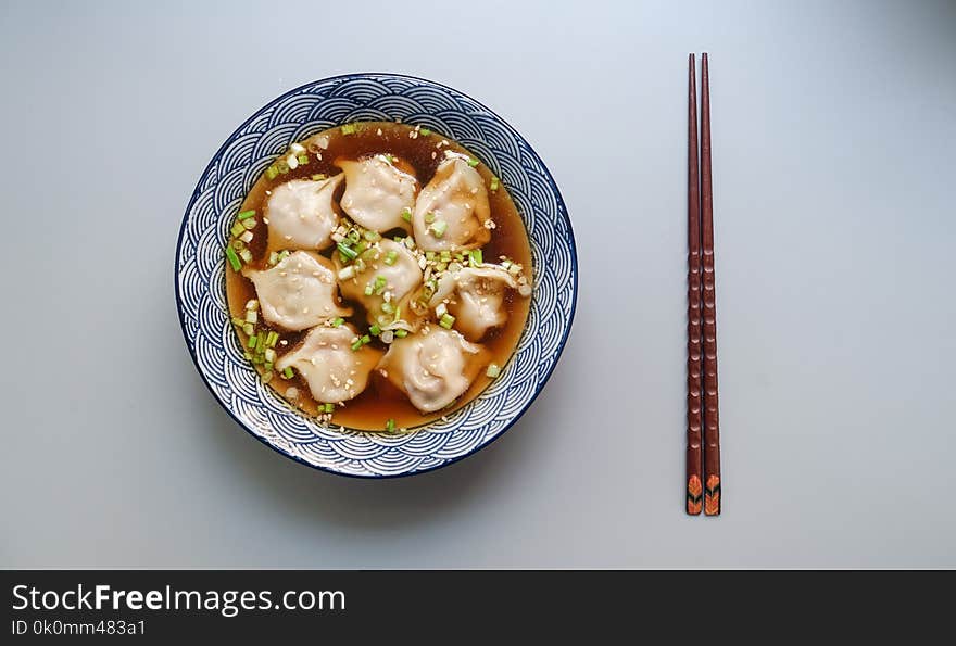 Round White and Blue Ceramic Bowl With Cooked Ball Soup and Brown Wooden Chopsticks