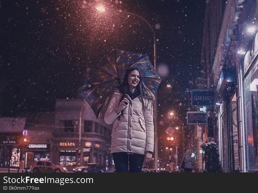 Woman Wearing Brown Bubble Jacket Holding Teal and Yellow Umbrella Near Building