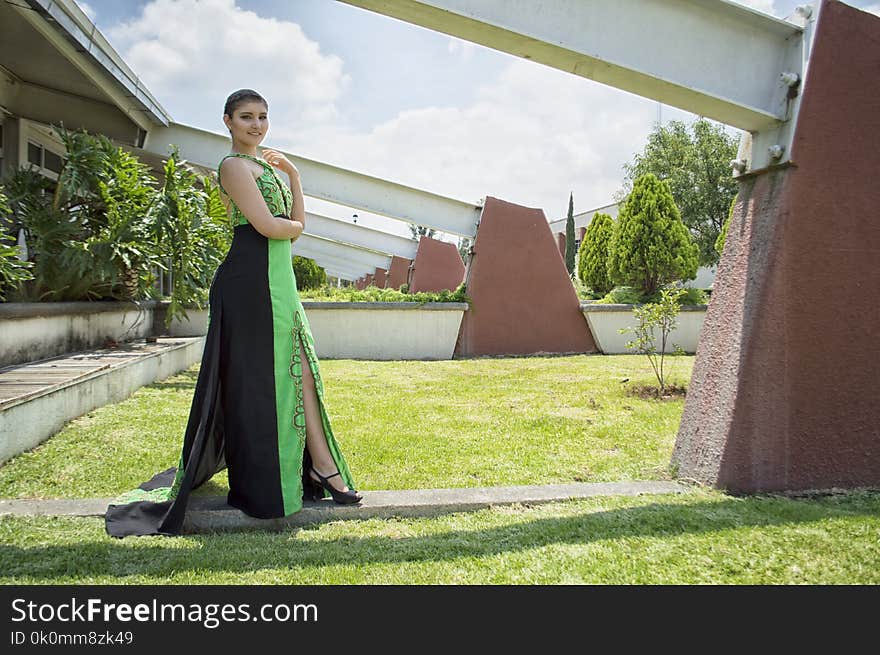 Woman in Green and Black Dress Standing in Front of Wall