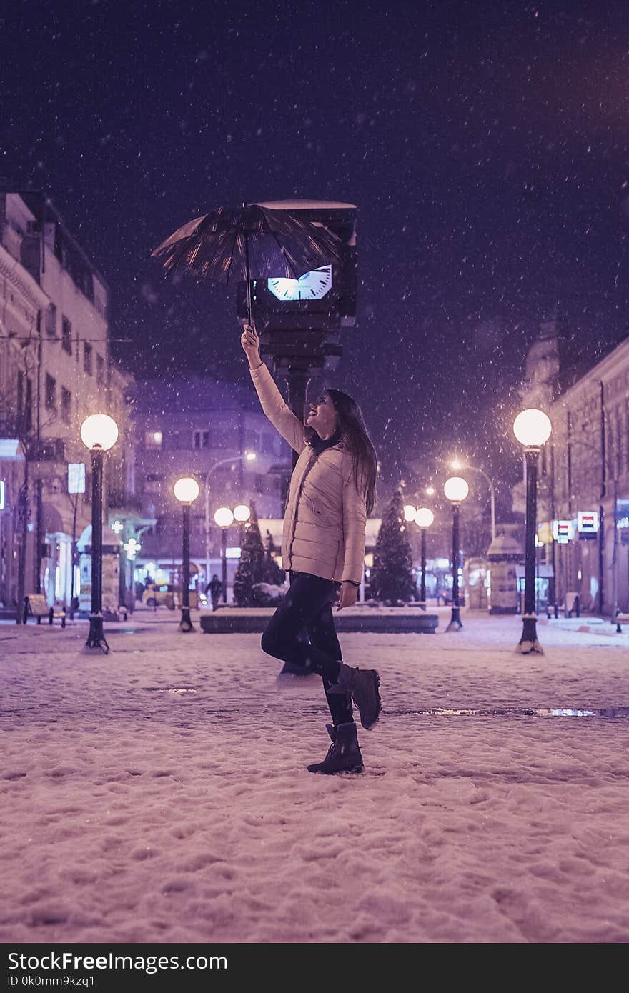 Woman in White Bubble Jacket and Black Jeans Standing While Holding Umbrella