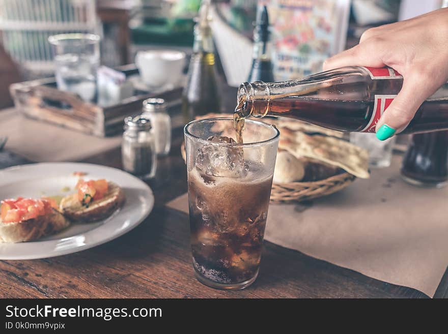 Photo of Cola Pouring Into a Glass with Ice Cubes