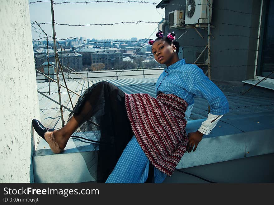 Woman in Blue and Red Dress Posing in Quirky Style on White Wall With Barb Wires