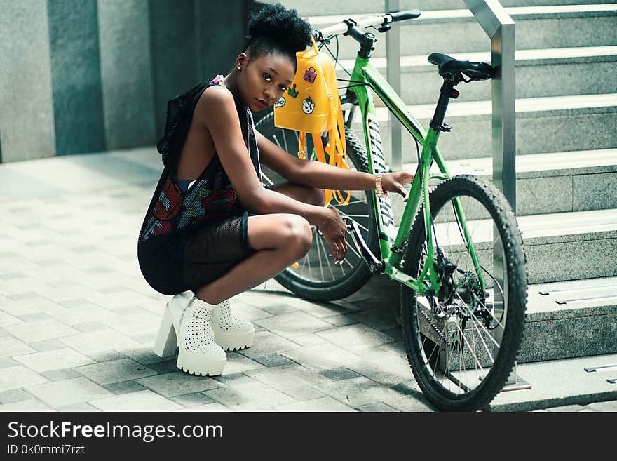 Woman Wearing Black Dress Seating Near Green Bicycle