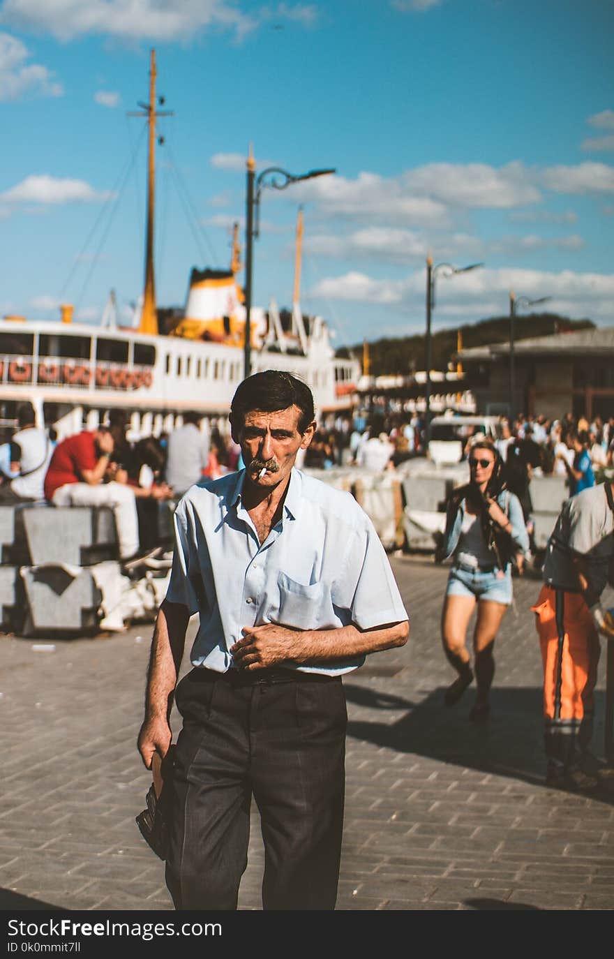 Man Wearing Blue Button-up T-shirt and Black Dress Pants Smoking Cigarette