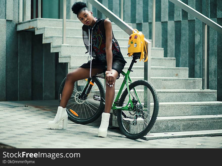 Woman in Black Sleeveless Dress Sitting on Green Bike