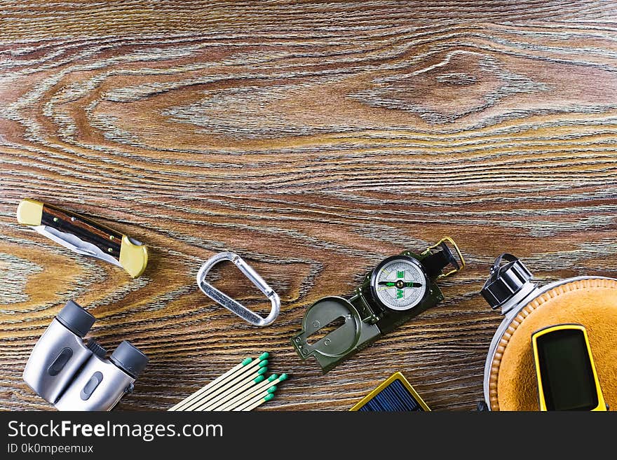 Hiking or travel equipment with compass, binoculars, matches on wooden background. Active lifestyle concept. Top view