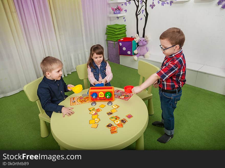 Teacher and children play a board game in the classroom. Teacher and children play a board game in the classroom