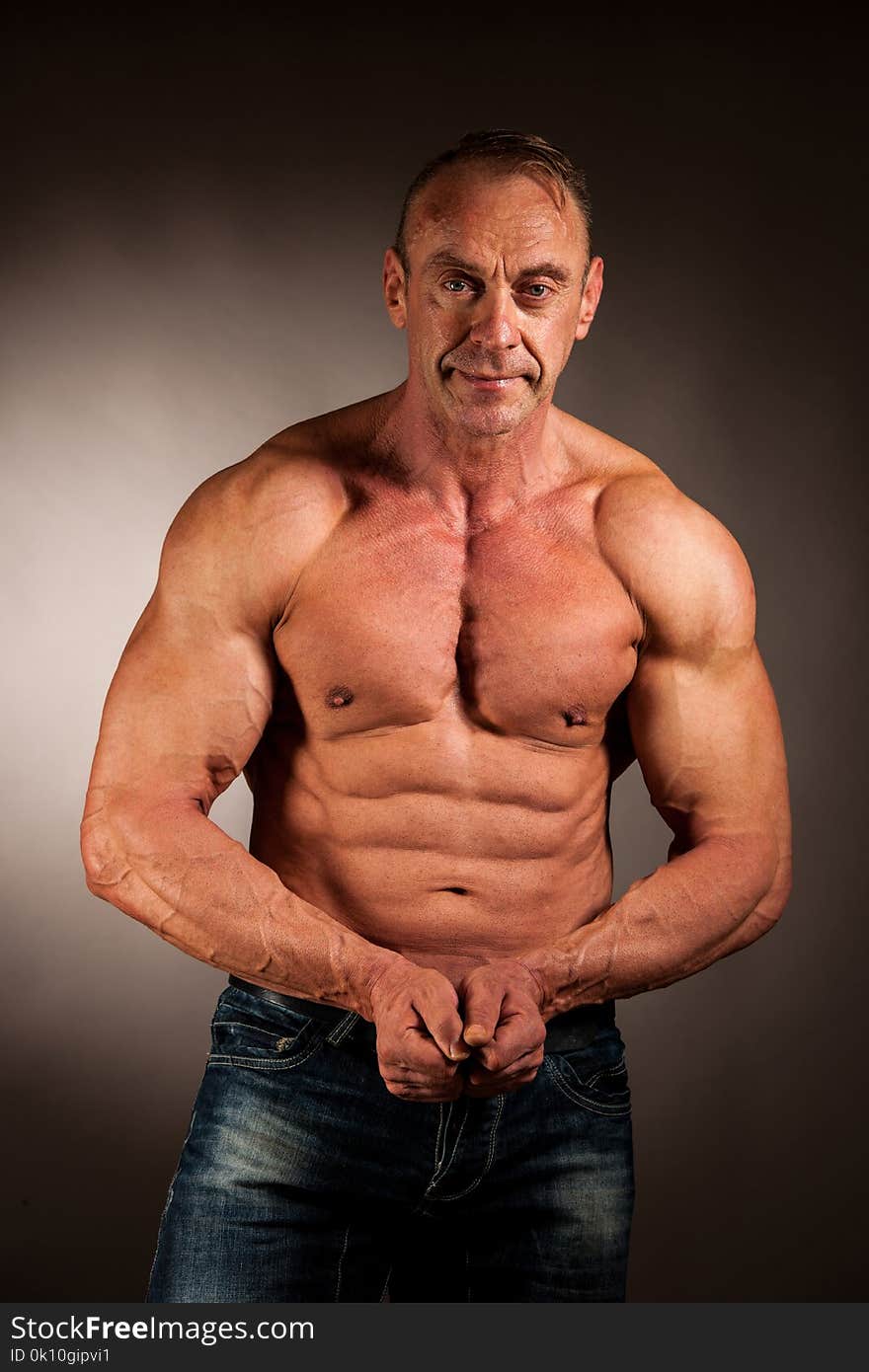 Bodybuilder Pose In Studio Over Dark Background