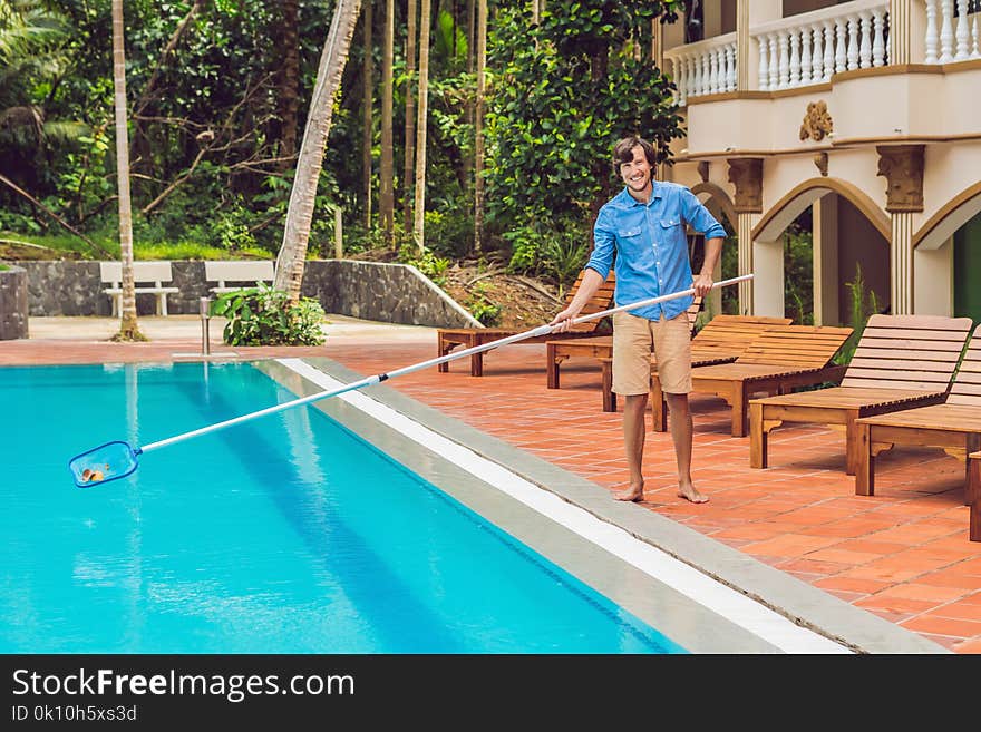 Cleaner of the swimming pool . Man in a blue shirt with cleaning equipment for swimming pools, sunny.