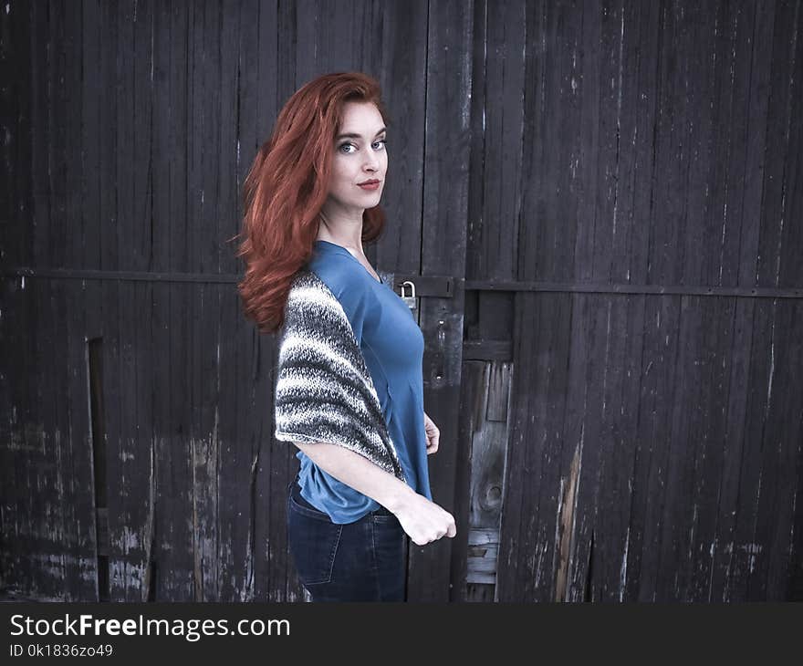 Photo of a Woman Wearing Blue Shirt Behind Black Wooden Wall