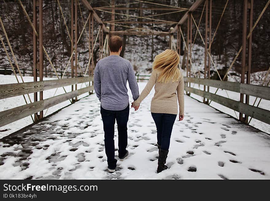 Man and Woman Walking on Snow Covered Road