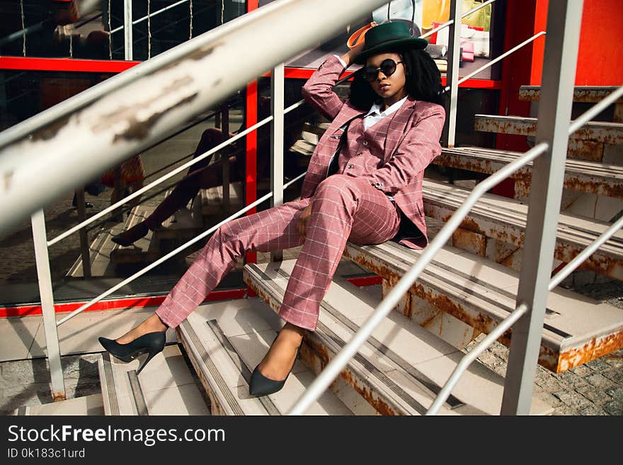 Woman Wearing Pink Suit Jacket and Pants Sitting on Staircase