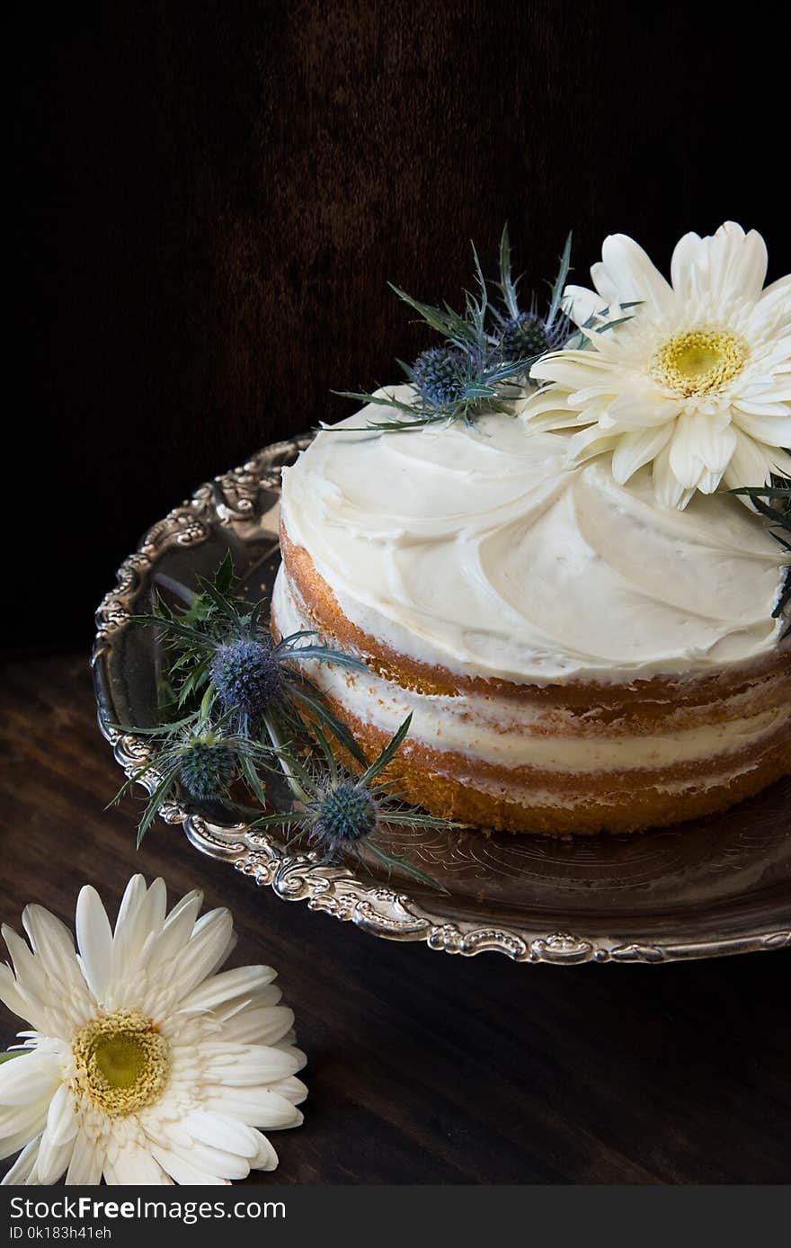 Fondant Cake Whipped With White Icing and Topped With White Petaled Flower on Grey Stainless Steel Plate