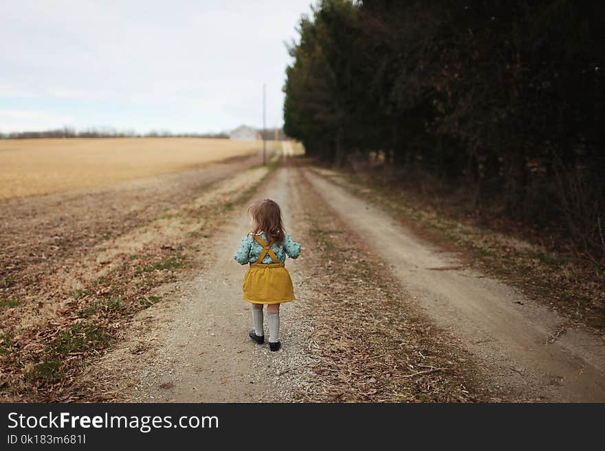 Girl Wearing Blue Long-sleeved Shirt and Yellow Skirt Walking on Pathway