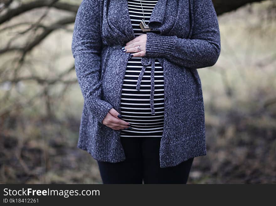 Woman Pregnant in Black and White Striped Shirt Standing Near Bare Tree