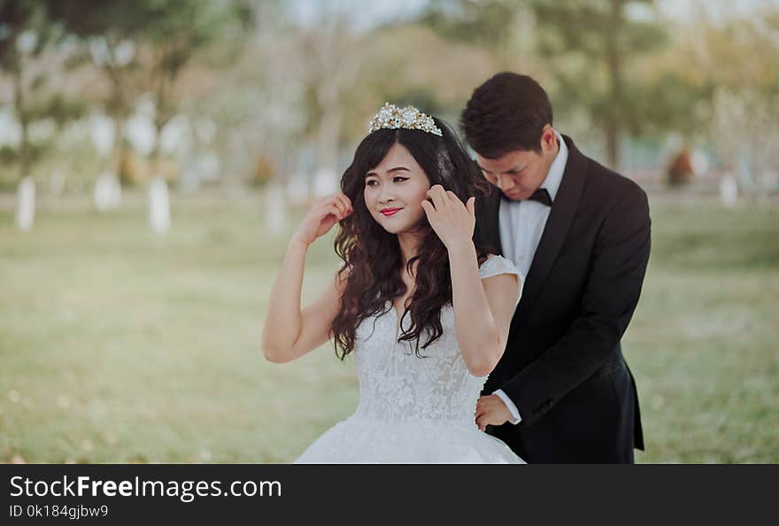 Groom Tying Bride&#x27;s White Lace Wedding Gown at the Back