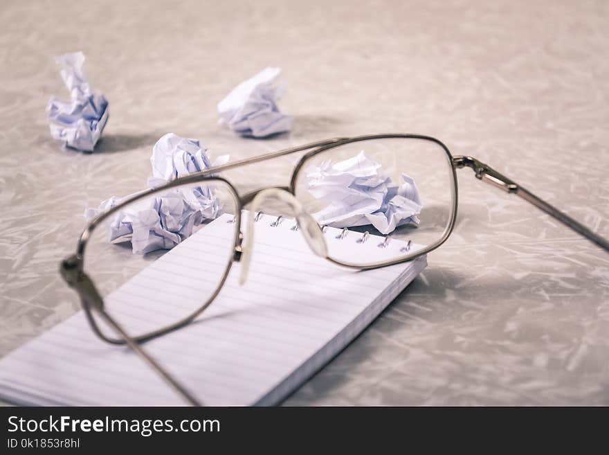 Close-Up Photography of Eyeglasses Near Crumpled Papers