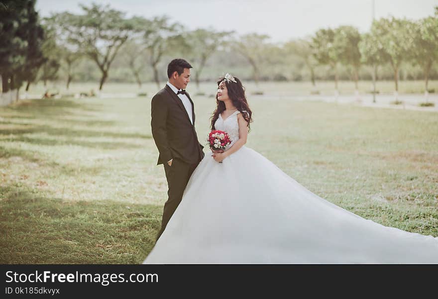 Woman Wearing Wedding Dress Standing Beside a Man Wearing Tuxedo