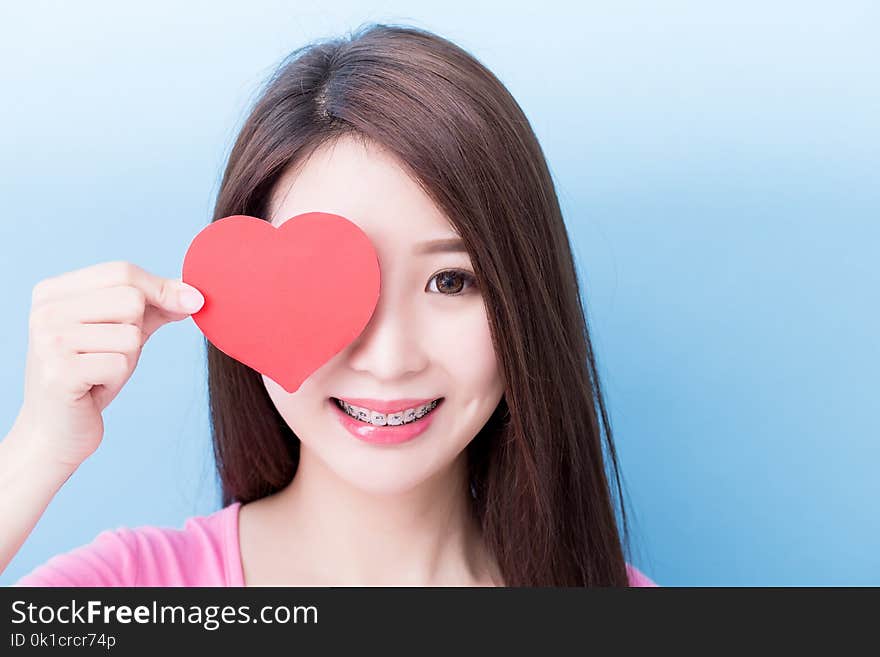 Woman wear brace and take heart on the blue background. Woman wear brace and take heart on the blue background