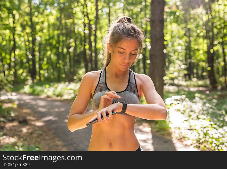 Young athlete woman checking fitness progress on her smart watch. Female runner using fitness app to monitor workout performance