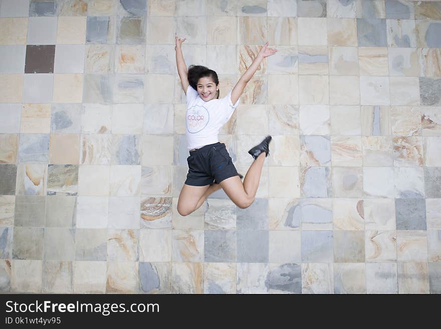 Woman in White Shirt and Black Shorts Taking Jump Shot Near Wall